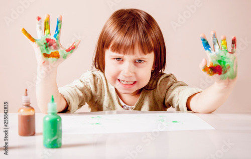 Beautiful little child girl with colorful painted hands. Funny portrait.