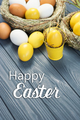 Yellow colored Easter eggs in nest on wooden background, selective focus image. Happy Easter card 