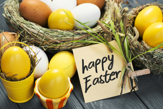 Yellow colored Easter eggs in nest on wooden background, selective focus image. Happy Easter card 