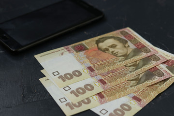Ukrainian banknotes one hundred hryvnia and smartphone, money background