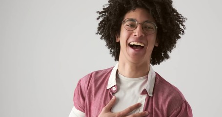 Egyptian man with curly hair laughing over white background