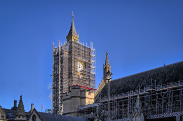 Fototapeta na wymiar The iconic London landmark Elizabeth Clock Tower, Big Ben, with one dial showing and covered in steel scaffolding for renovations and repair.