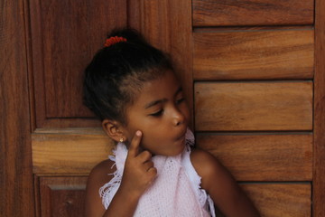 Portrait of cute little girl thinking. She has her old wooden door. African-American mixed race child.