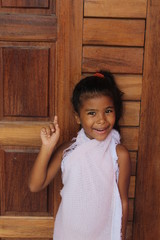 Portrait of cute little girl thinking. She has her old wooden door. African-American mixed race child.