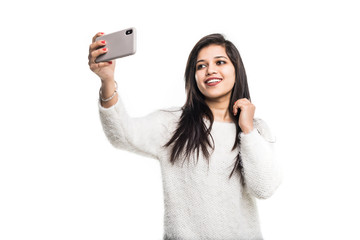 Indian young girl taking selfie with smartphone isolated on white background