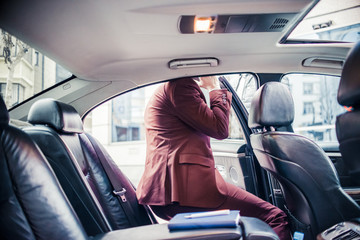 Businessman in purple suit getting in the car