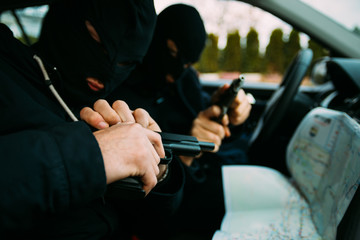 Bank robbers with their masks on pointing at the map prepared for robbing the bank,sitting in the...