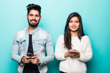 Indian couple typing mobile phone isolated on green background