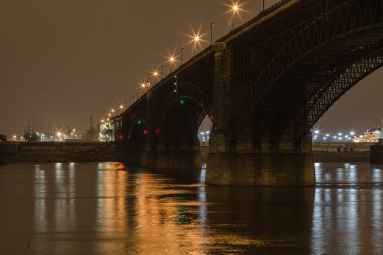 Classic stone bridge over Mississippi River with calm water at night with lights reflecting