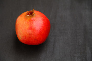 Ripe pomegranate berries in a bowl, on the black wooden, close up on 