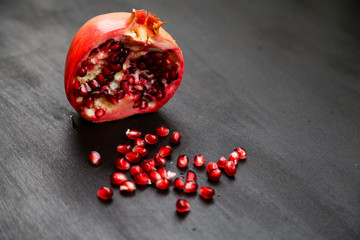 Ripe pomegranate berries in a bowl, on the black wooden, close up on 