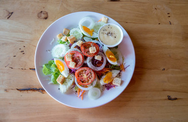 Fresh salad with vegetables tomatoes, cucumbers, lettuce, salad leaves and eggs on grey background top view and copy space. Vegetarian food. Healthy food and diet concept. 