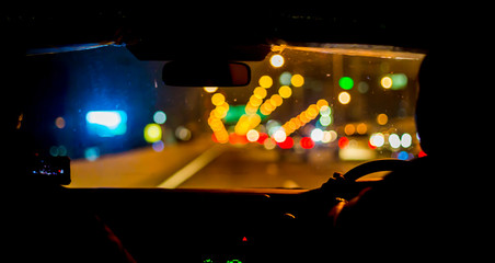 Selective focus of man driving a car at night. View from inside the car.