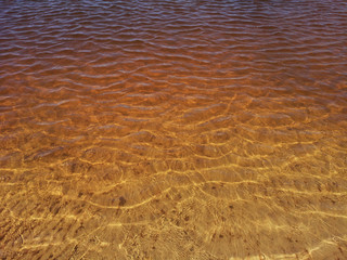 Abstract golden texture of ripples on the crystal water