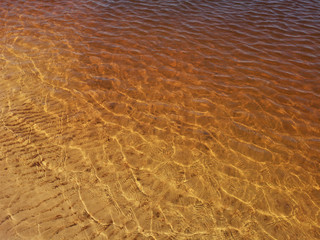 Abstract golden texture of ripples on the crystal water