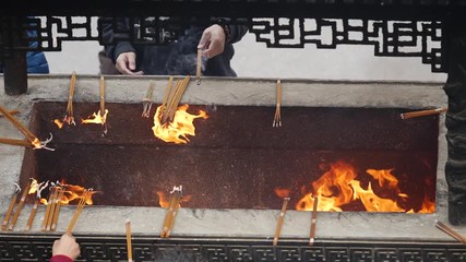 Slow motion fire and incense smoke in traditional Chinese temple, prayers put burning incense into incense burner, FHD movie, 180 FPS.