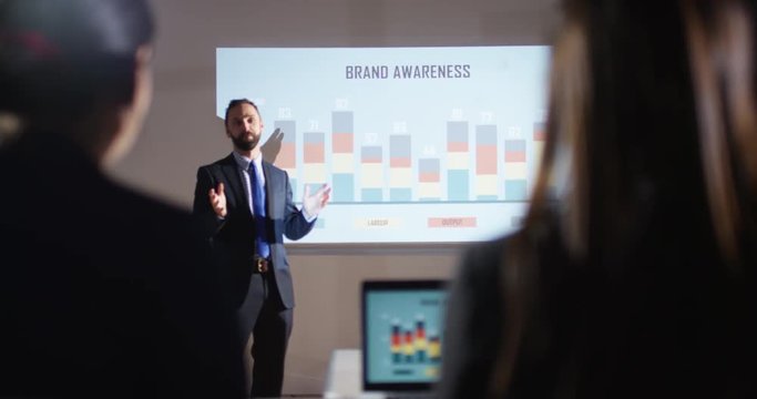 4K Marketing businessman giving a presentation showing animated graphs on screen