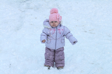 Fototapeta na wymiar Little beautiful baby girl standing in the winter on the street.