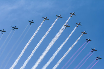 Los doce aviones acrobáticos están echando humo de color verde, blanco y rojo.