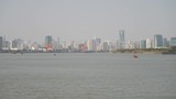 shanghai bund viewed from Xuhui Bingjiang Park, skyscrapers with blue sky background, cargo ships sailing on Huangpu river, 4K video, slow motion.
