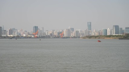 shanghai bund viewed from Xuhui Bingjiang Park, skyscrapers with blue sky background, cargo ships sailing on Huangpu river, 4K video, slow motion.