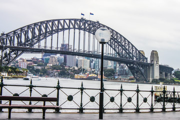 View of Sydney Harbour Bridge from the Circular Quay on a wet morning, with city in the distance and a ferry crossing over