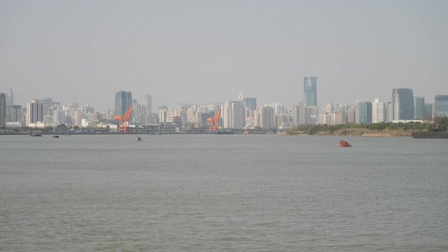 shanghai bund viewed from Xuhui Bingjiang Park, skyscrapers with blue sky background, cargo ships sailing on Huangpu river, 4K video, slow motion.