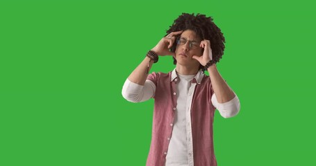 Young man suffering from headache over green chroma key background