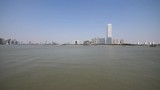 shanghai bund viewed from Xuhui Bingjiang Park, skyscrapers with blue sky background, cargo ships sailing on Huangpu river, 4K video, slow motion.