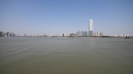 shanghai bund viewed from Xuhui Bingjiang Park, skyscrapers with blue sky background, cargo ships sailing on Huangpu river, 4K video, slow motion.