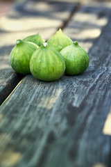 A group of five freshly picked ripe figs on a wooden bench with space for copy.