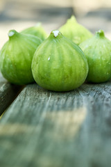 A group of five freshly picked ripe figs on a wooden surface.