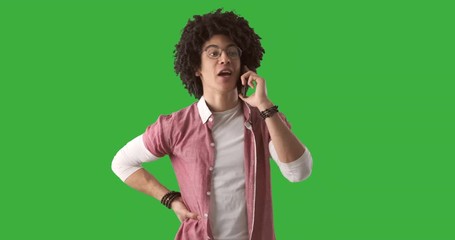 Man with curly hair talking on mobile phone over green chroma key background