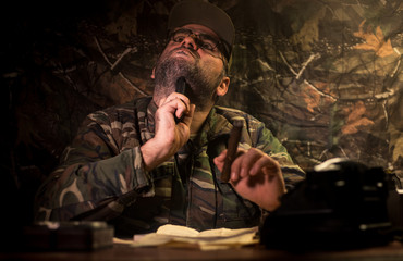 The evil dictator sitting on table. Angry communist general sitting at headquarter or Cuban commander in dark room.