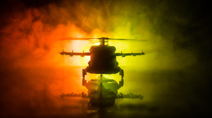 Silhouette of military helicopter ready to fly from conflict zone. Decorated night footage with helicopter starting in desert with foggy toned backlit. Selective focus. © zef art