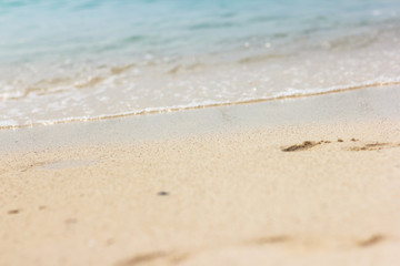 Fototapeta na wymiar Footprints in the sand. Beautiful sandy tropical beach with sea waves. Footsteps on the shore.