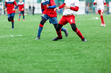 Boys in red white sportswear running on soccer field. Young footballers dribble and kick football ball in game. Training, active lifestyle, sport, children activity concept