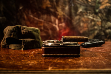 Close up of a Cuban cigar and ashtray on the wooden table. Communist dictator commander table in...