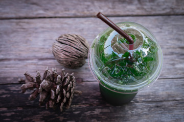 Iced green tea honey lemon drink with dried pine cones on wooden table background