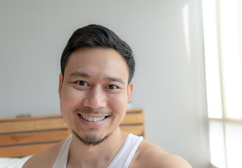 Close up smile happy face of Asian man in his bedroom in the morning.