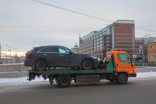tow truck carrying a black car on a bridge in winter