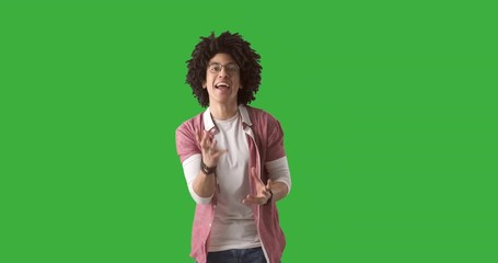 Excited young man celebrating success over green chroma key background