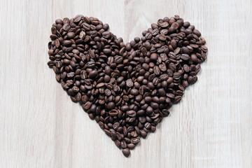 Heart shape arranged by coffee beans and wood pattern as background