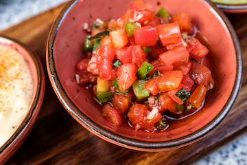 Close up bowl of fresh homemade Pico De Gallo salsa dip on wooden tray