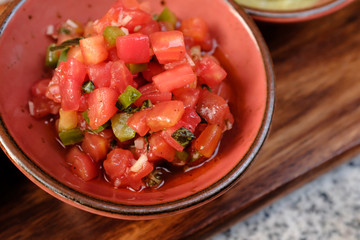 Close up bowl of fresh homemade Pico De Gallo salsa dip on wooden tray