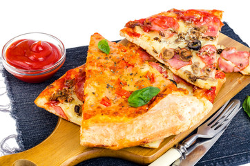 Slices of pizza on wooden board on jeans.