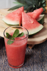 Glass of watermelon smoothie with some slice of the fruit on the background