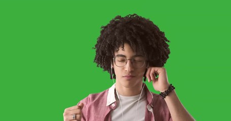 Happy man listening music on earphones over green chroma key background