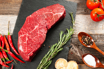 Raw meat, beef with spices for cooking on black board