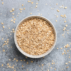 Rolled oats in bowl, healthy food, healthy eating concept. Organic oat flakes on concrete...